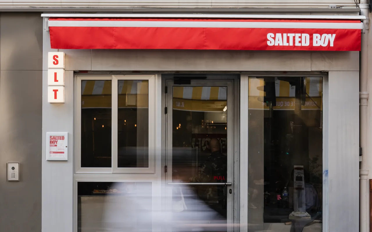 La façade Salted Boy : store banne rouge, enseigne lumineuse SLT et vitrine sur rue.