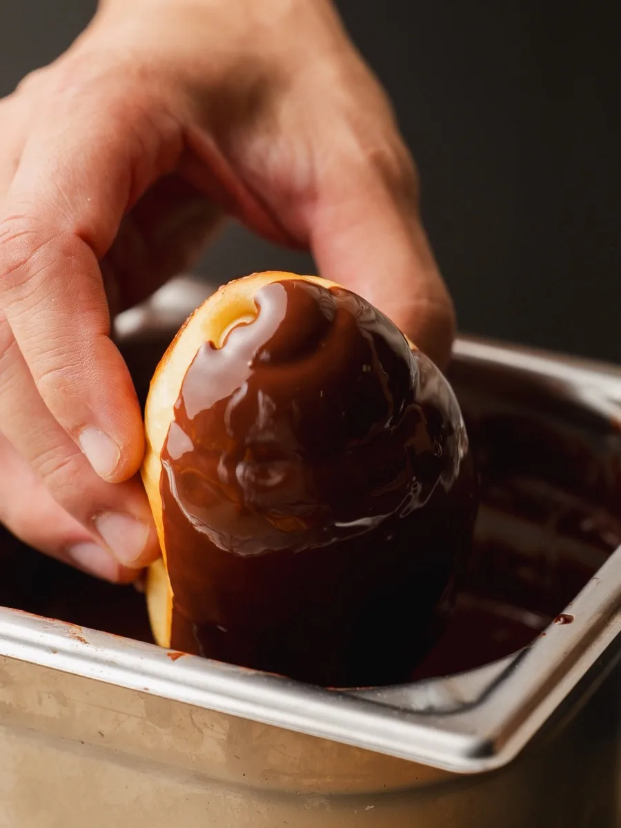 Un salted bread trempé à la main dans un bac de chocolat fondu.